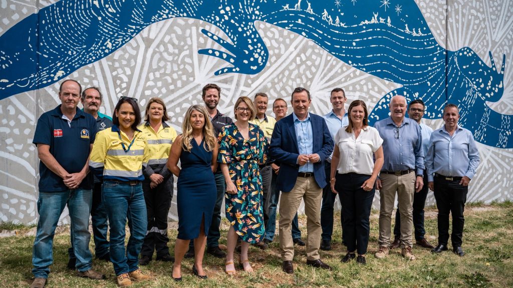Just Transition Working Group members with the Premier in Collie Just Transition Working Group members standing against a mural wall